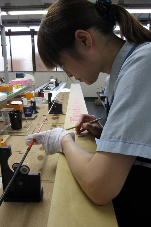 Technicienne en train d'appliquer une couche de vernis sur la canne 